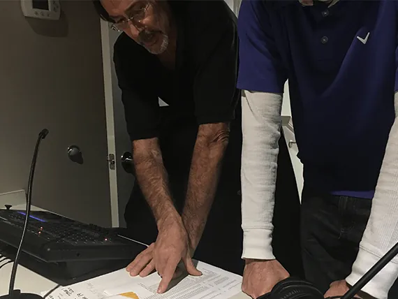 A trainer walking a volunteer through operating a mixing console